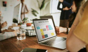 Group meeting around a table with a laptop showing a digital marketing strategy dashboard