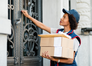 Mail carrier holding packages and knocking on a residential door, delivering direct mail.