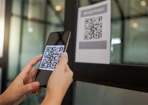 Person scanning a QR code printed on a sign for information or promotion access.